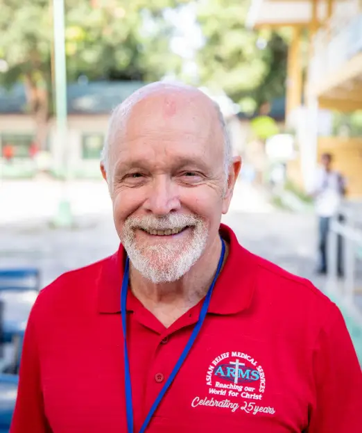 Pastor Glenn Kennedy smiling, wearing a red ARMS shirt