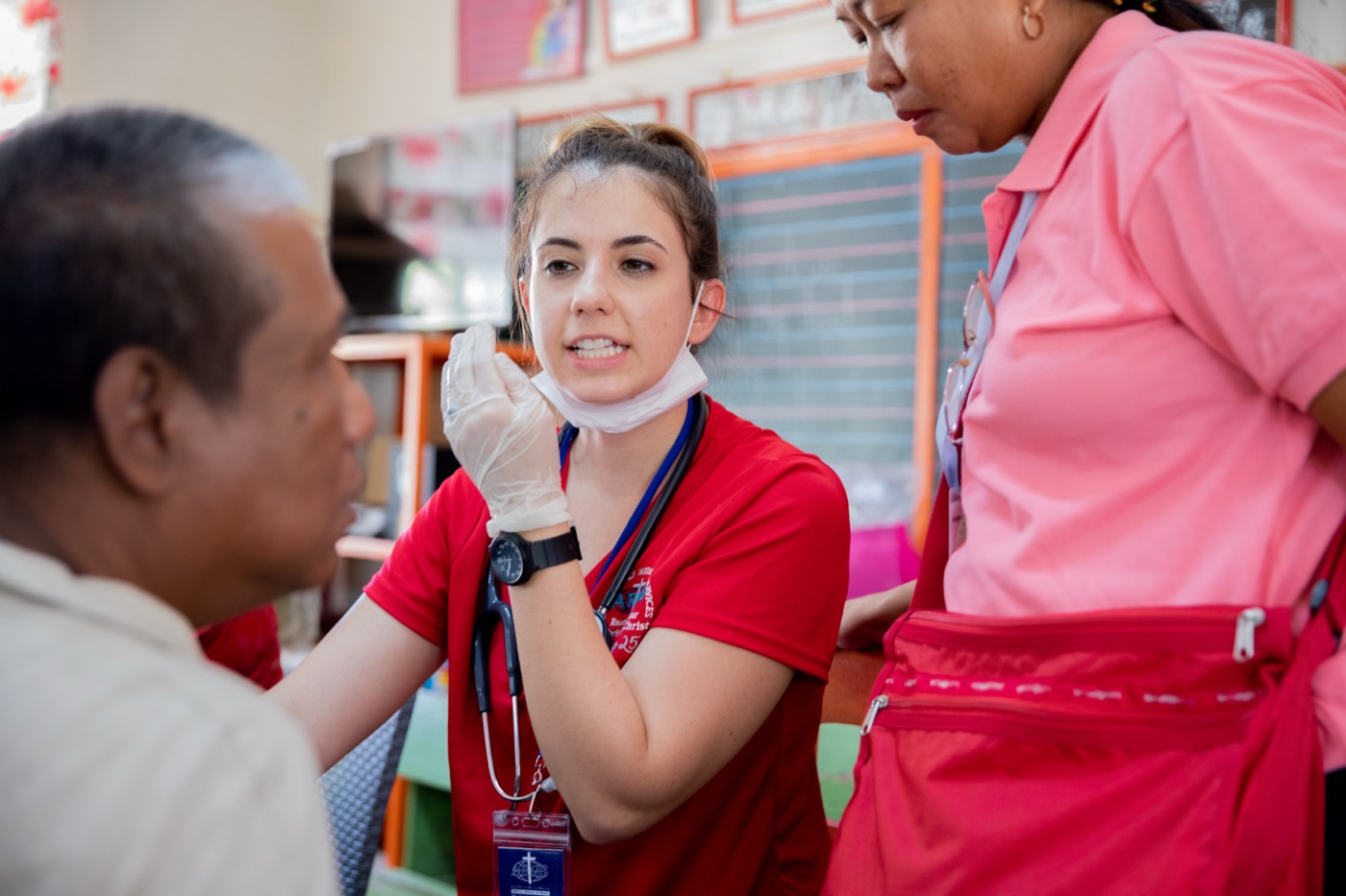Two ARMS volunteers speak with a patient during a clinic.